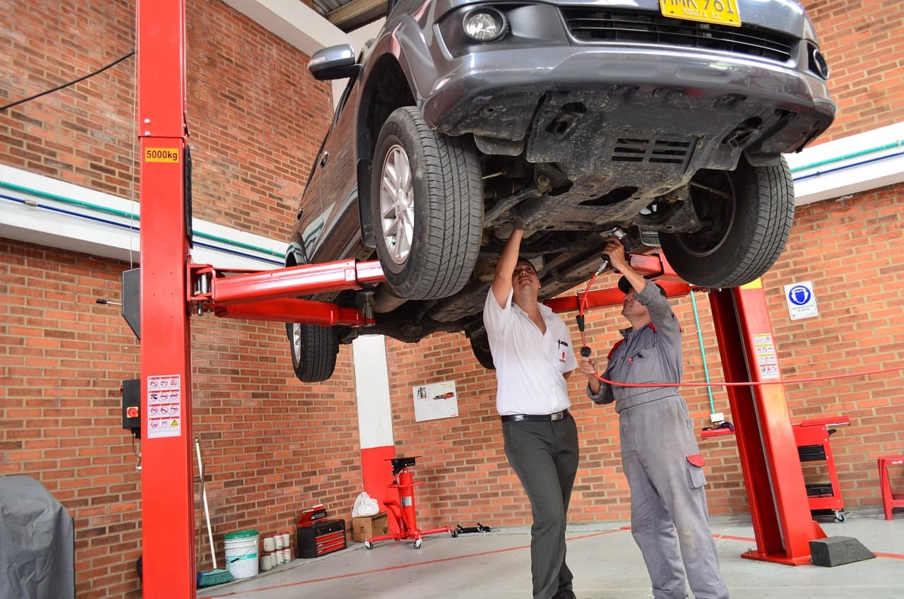 Two people inspecting the underside of a raised car